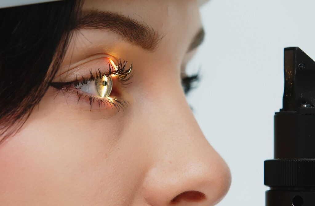 Close up of a woman in front of a vision testing equipment shining light into her right eye.