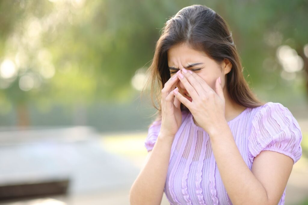 Woman rubbing her dry, irritated eyes outdoors.