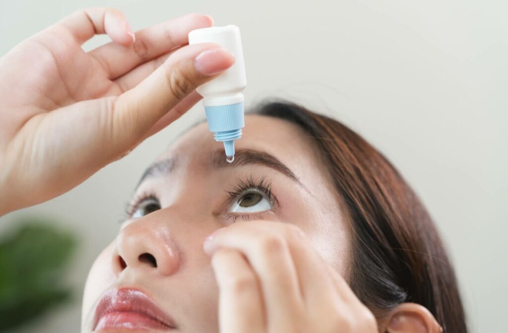 A person applying artificial tears to their dry eyes.