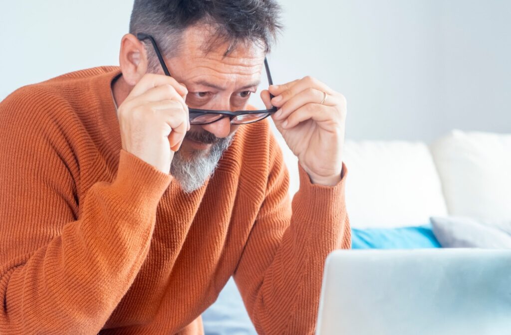 Man experiencing eye strain while using a laptop.