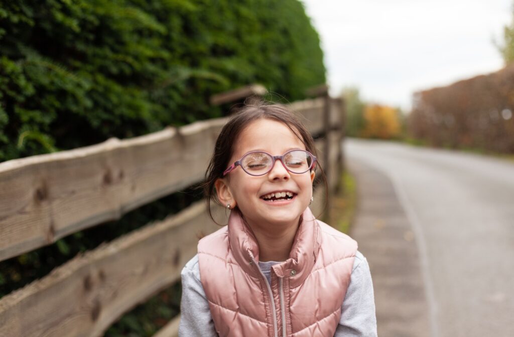 A child with glasses spending time outdoors to slow the progression of myopia symptoms.