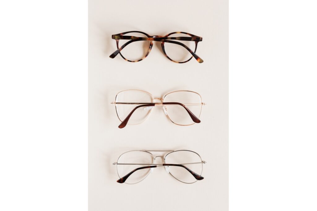 Three pairs of eyeglasses displayed on white surface showing different frame styles including tortoiseshell round frames and metal aviator designs.