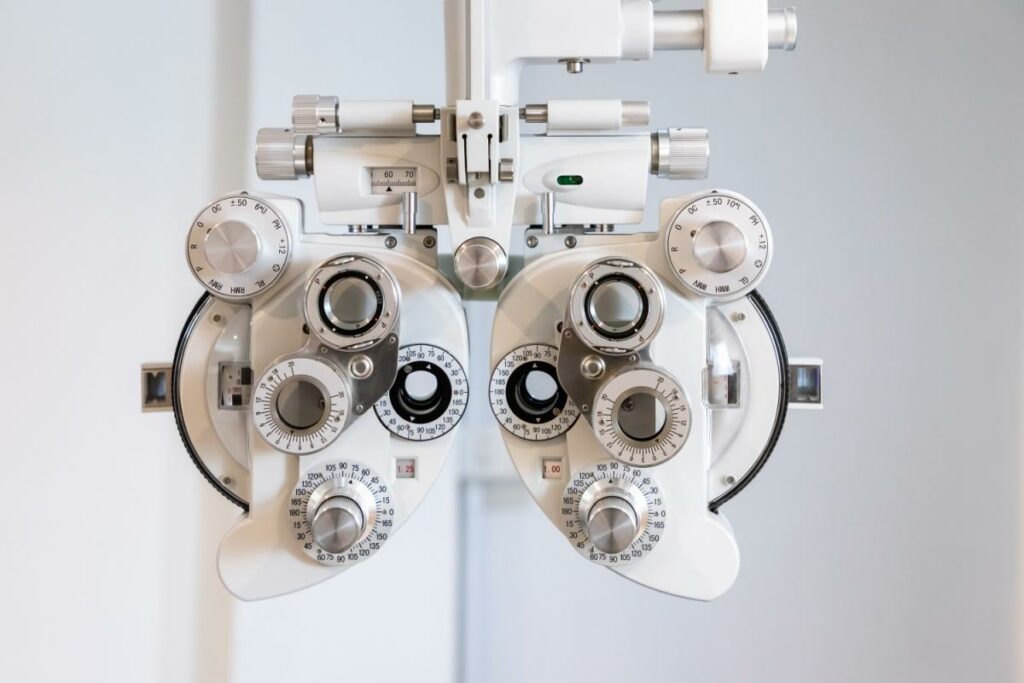 Image of a modern phoropter in a brightly lit optometrist exam room.
